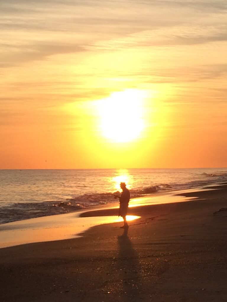 Silhouette of person at sunset beach.