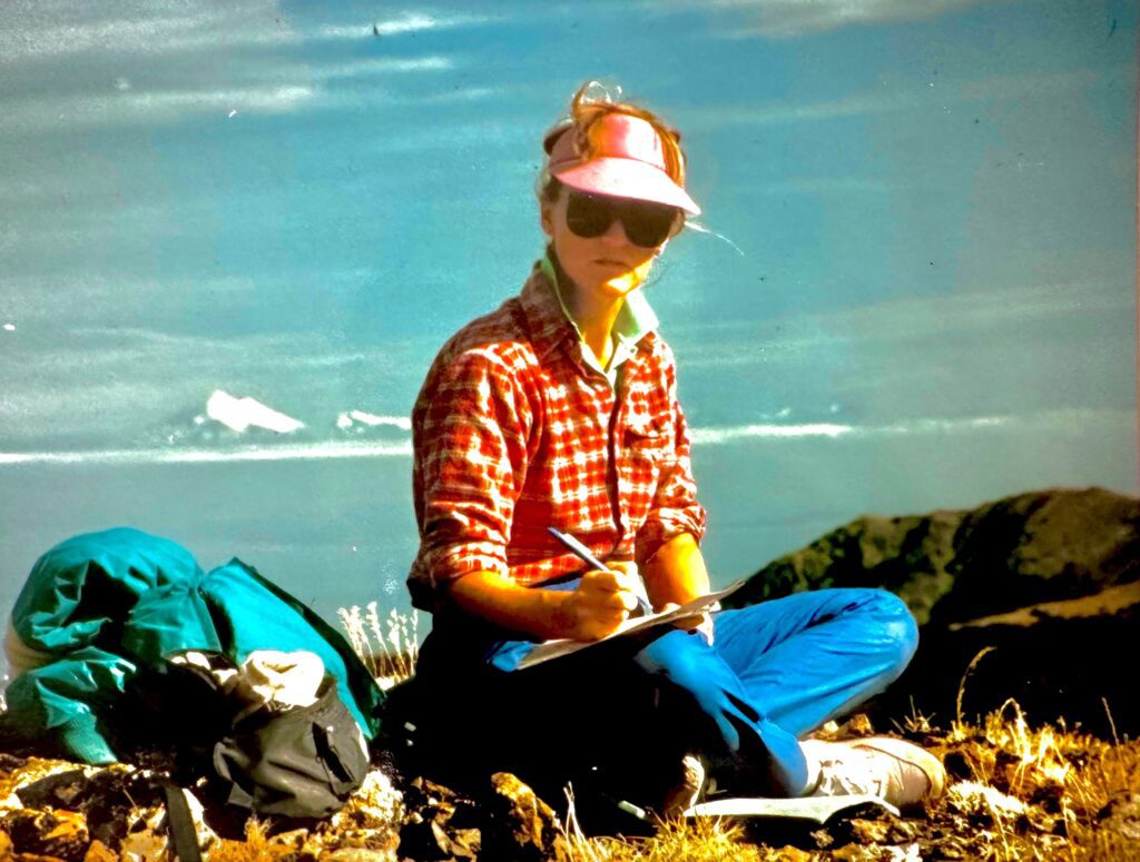 Woman writing in notebook outdoors.
