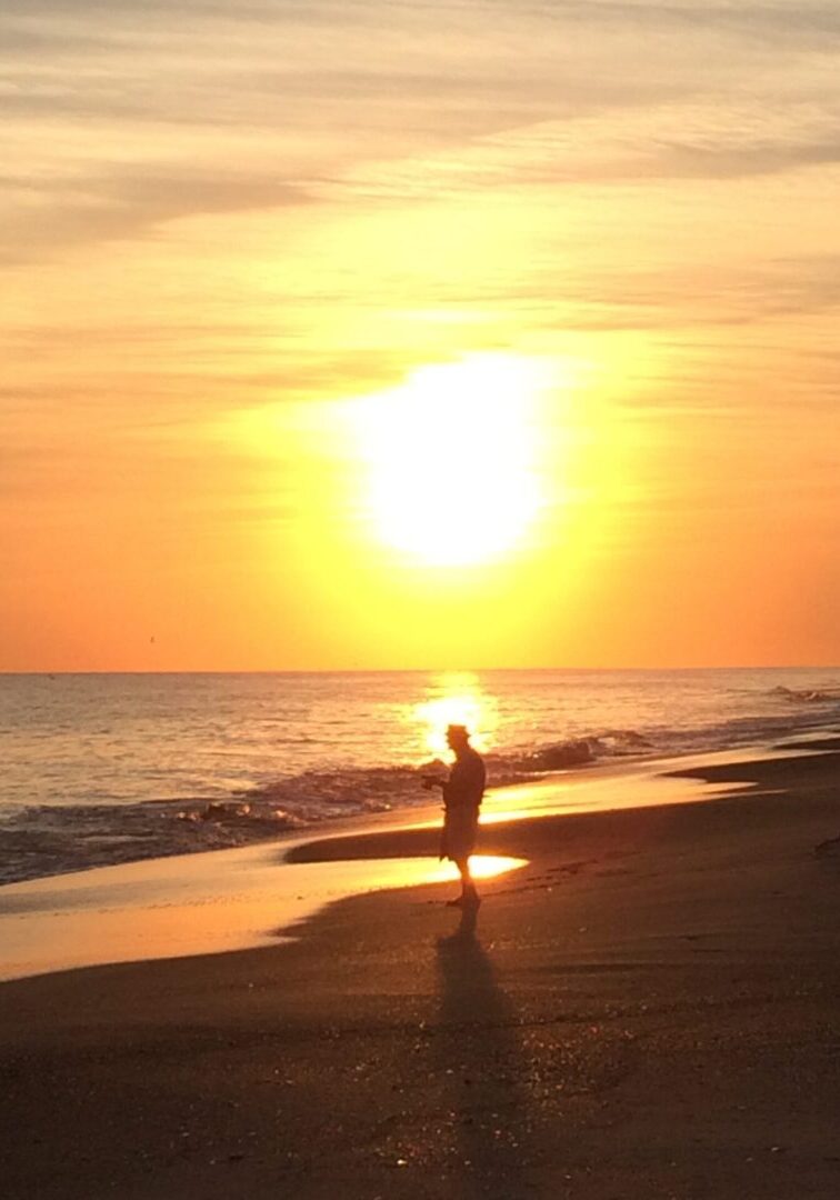 Silhouette of person at sunset beach.